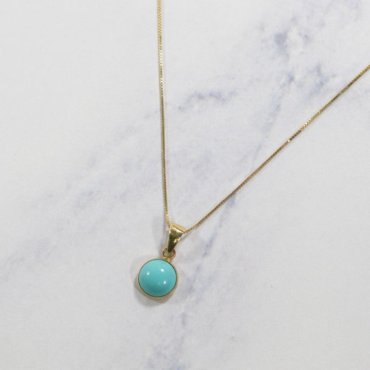 Круглый кулон из 14-каратного золота с искусственной бирюзой.