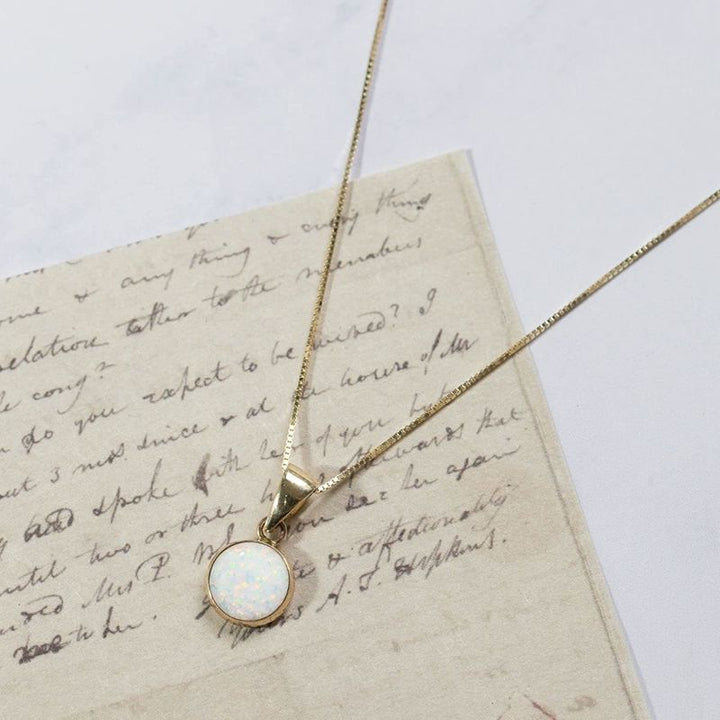 Круглый кулон из 14-каратного золота с белым опалом.